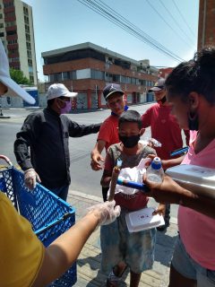 People giving out meals in boxes on a street corner