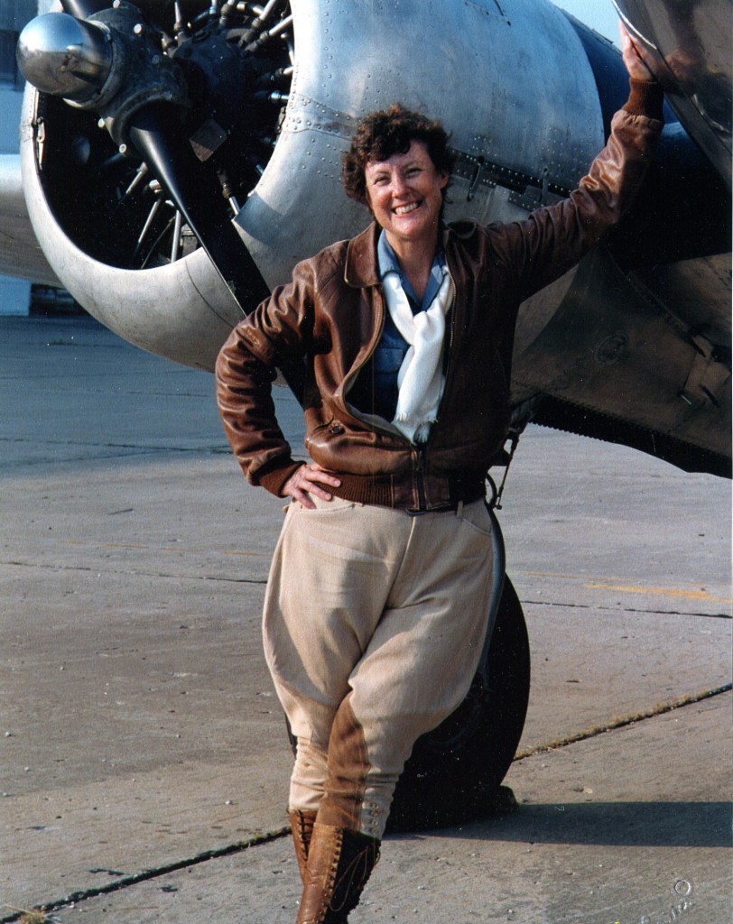 Ann Birney dressed as Amelia Earhart in front of a plane