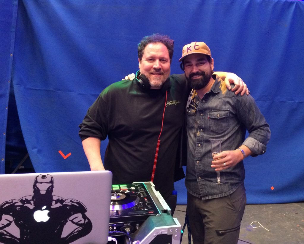 A photo of Barry wearing a KC baseball cap and holding a glass of champagne, with his arm around actor and filmmaker Jon Favreau, who he worked with on The Jungle Book