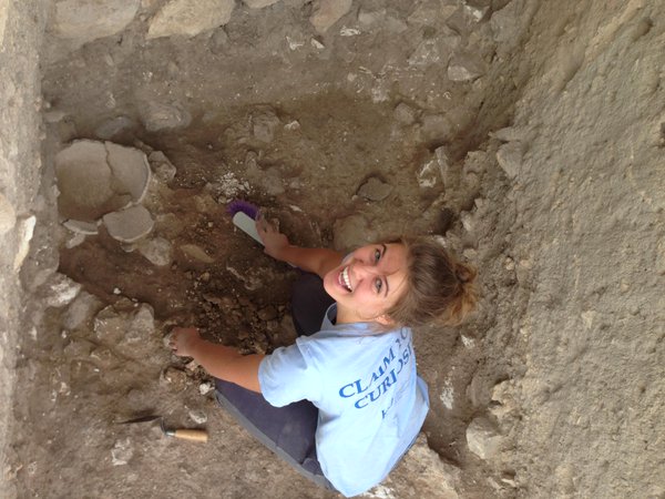 A student at an excavation site in a hole looking up