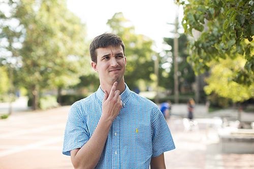 A man looks upward, touching his chin looking contemplative