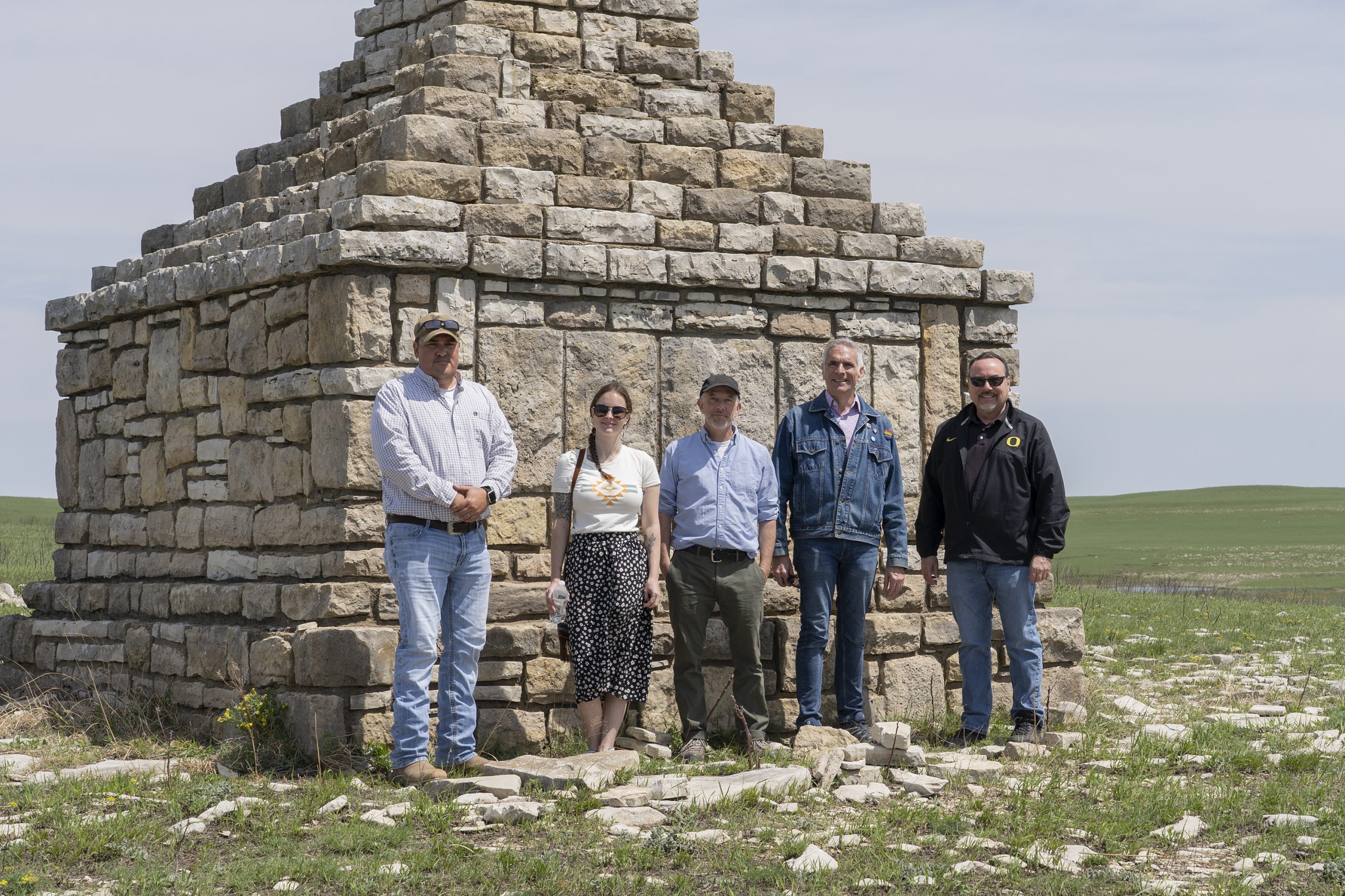 A group of people stand in front of a stone monument