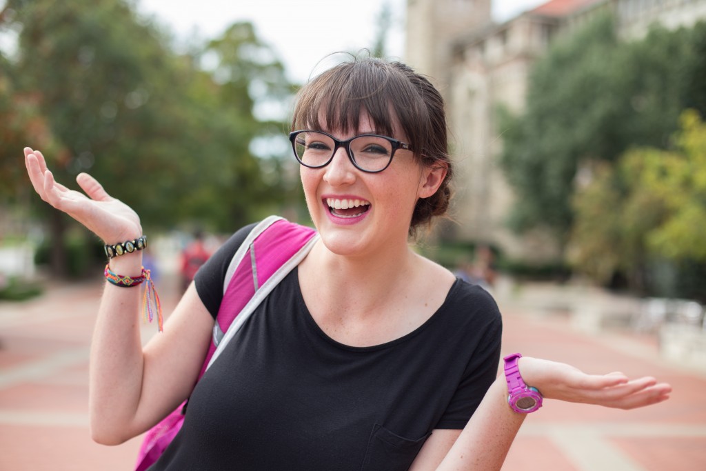 a woman with black glasses smiling and shrugging