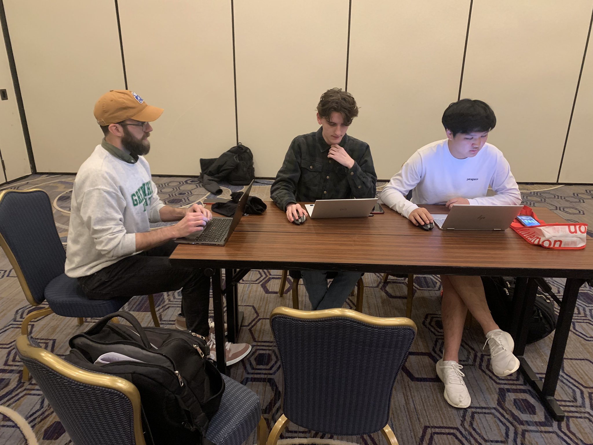 3 students on laptops at a table