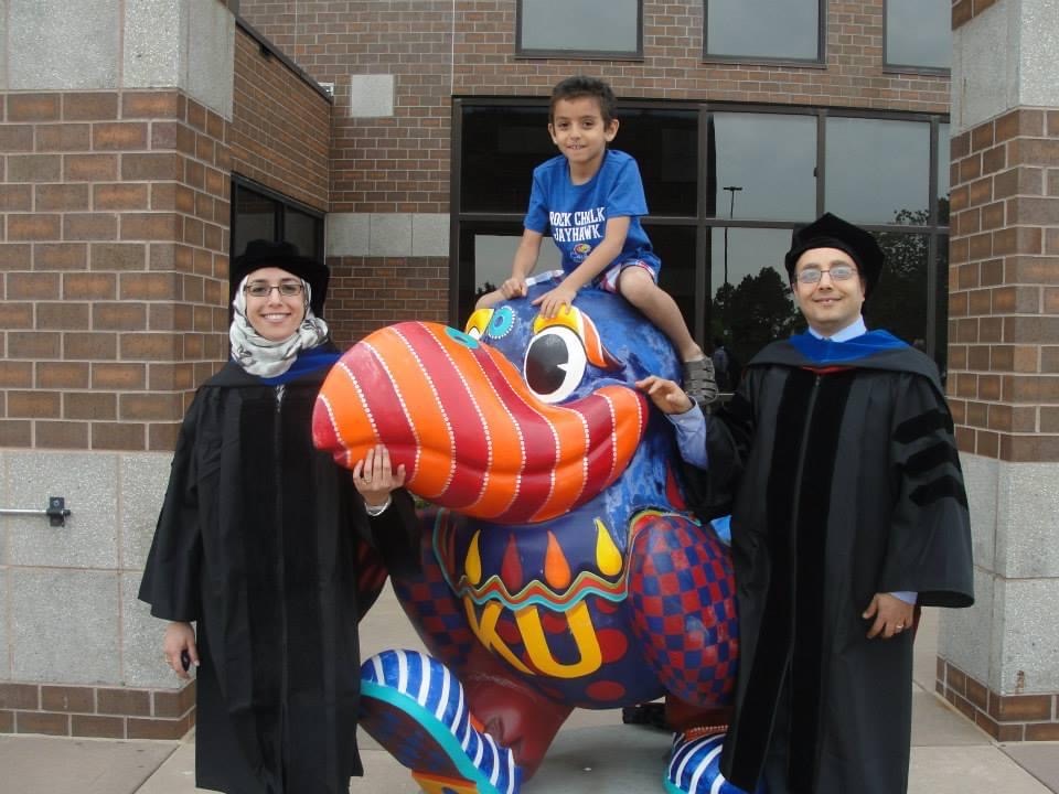 Heba Mostafa with family in graduation gown with the Jayhawk statue