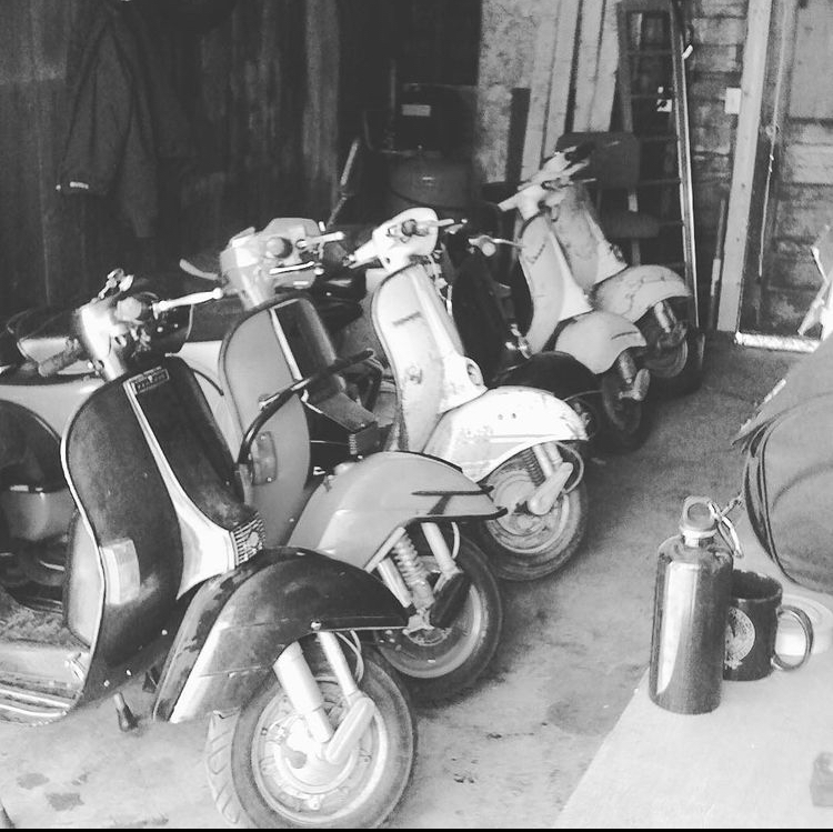 A black and white photo of Vespas in a garage