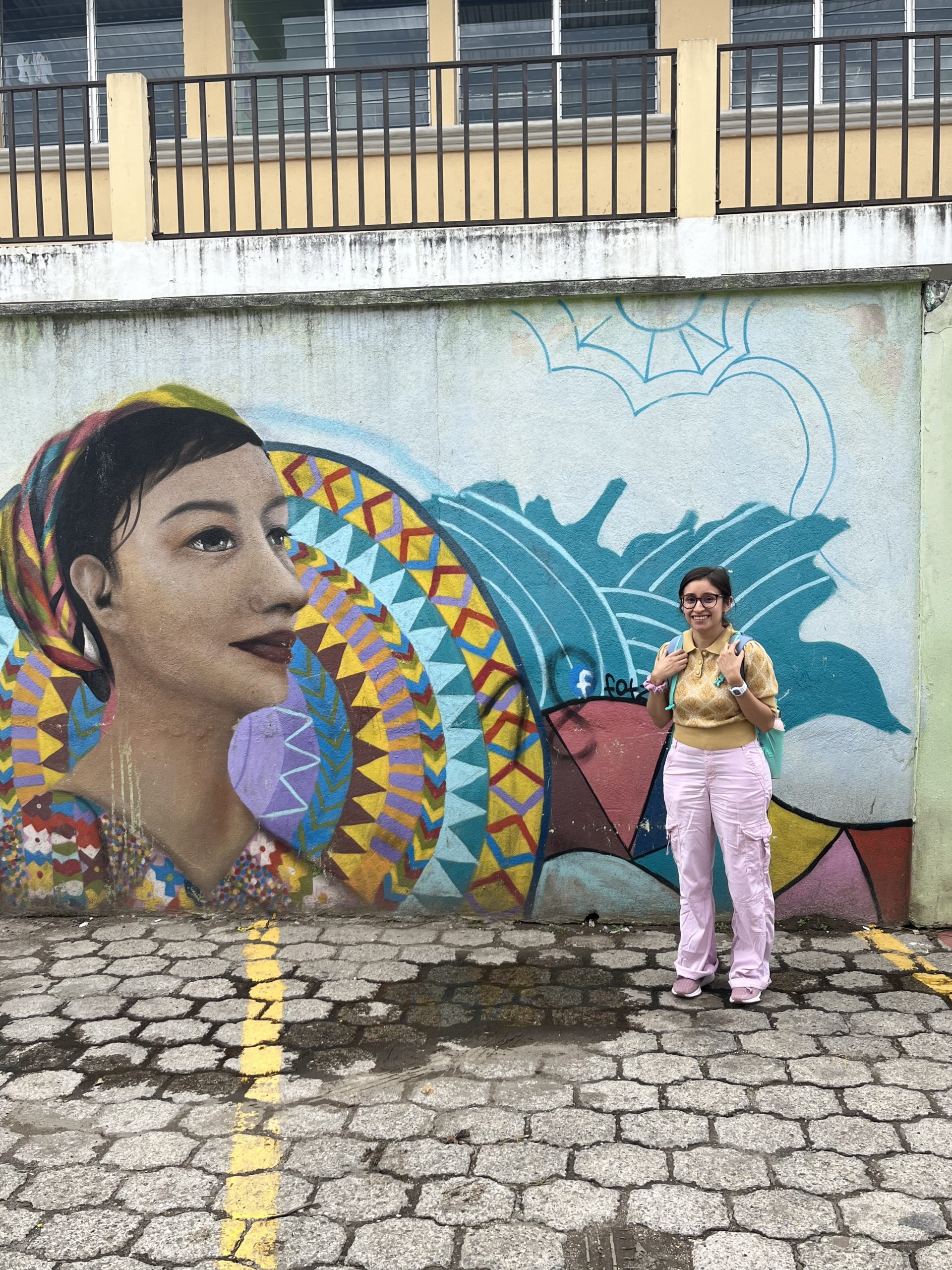 Margarita in front of a mural of a woman's face