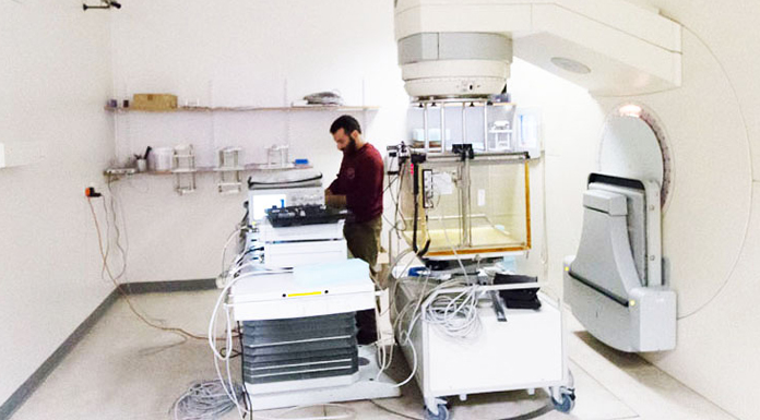 Man wearing red sweater looking at radiation equipment.