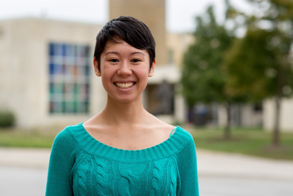 A woman smiling in front of the religious studies center on KU campus