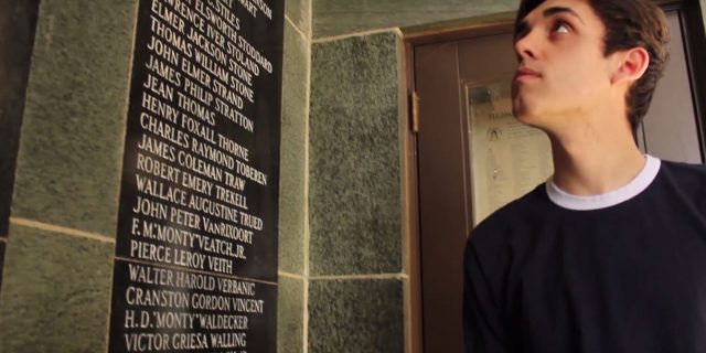 Korbin Painter looking at a plaque of names