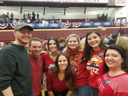 People posing and smiling in a large room with Americana decorations