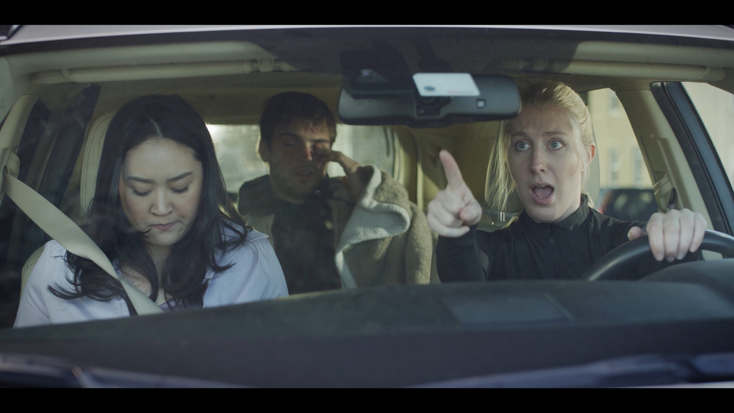 Chloe in a car scene in the driver's seat with two other passengers