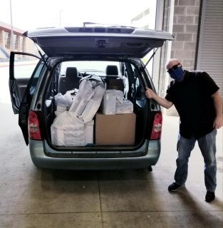 a person gestures at supplies in the back of a van