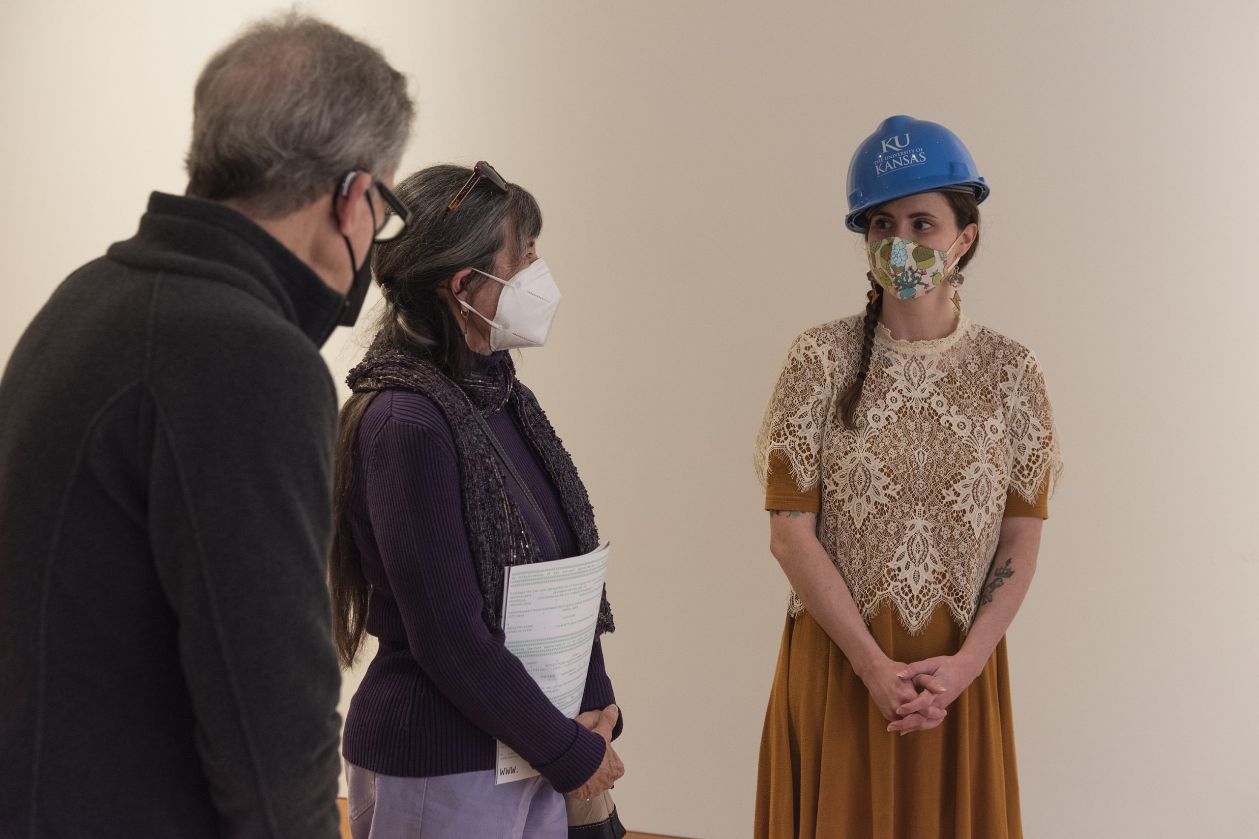 Sydney Pursel in a hard hat talking to two people