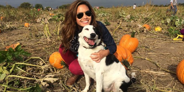 Cryslte with her dog on a pumpkin patch field