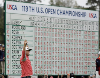 Gary Woodland raising his hands in the air in front of a scoreboard for the 119th U.S. Open Championship